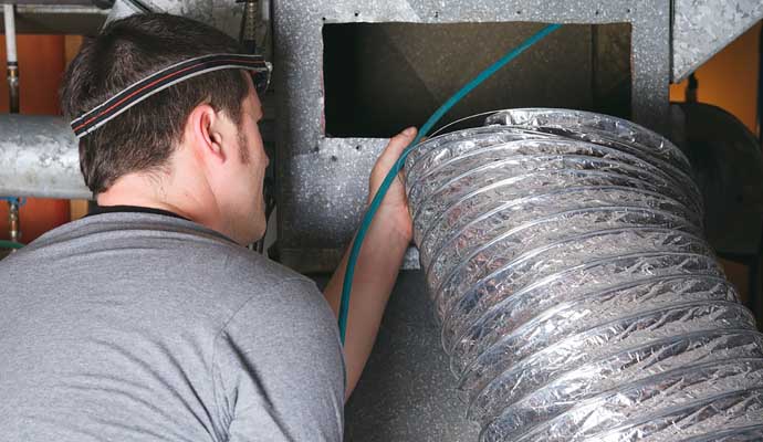 Technician installing ductwork for HVAC system