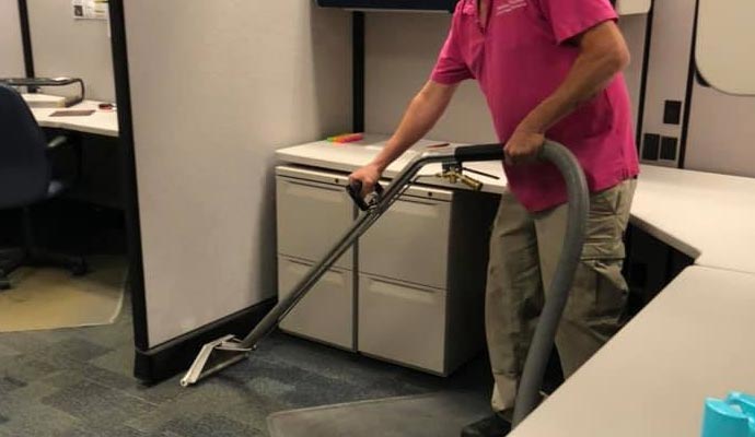 professional cleaner cleaning carpet with equipment