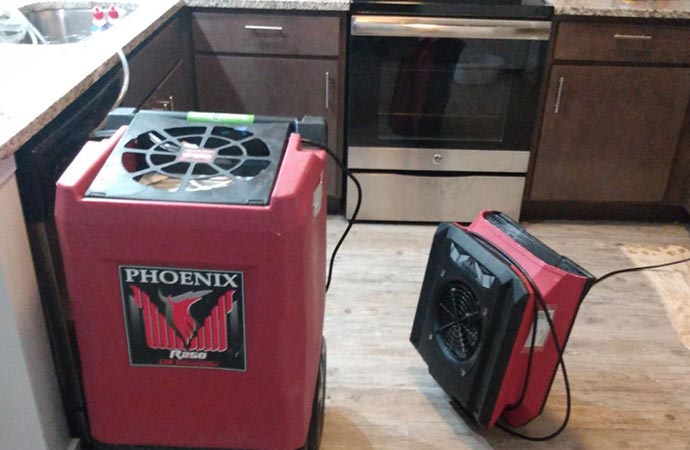 A red Phoenix dehumidifier is sitting on a floor in a kitchen