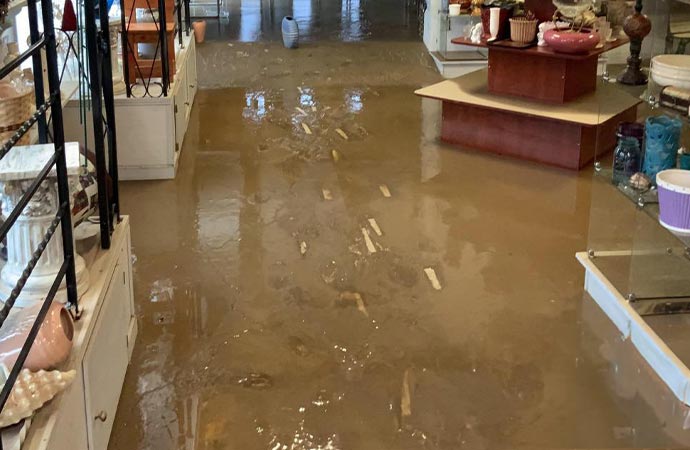 A store's interior flooded with brown water, damaging inventory.