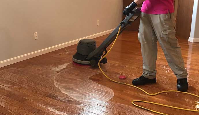 a person using a floor buffer to clean a laminate floor.