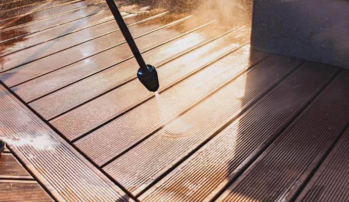 a wooden deck being cleaned with a high-pressure water cleaner