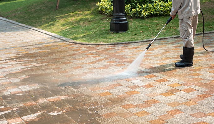  a person cleaning a driveway using a high-pressure water cleaner