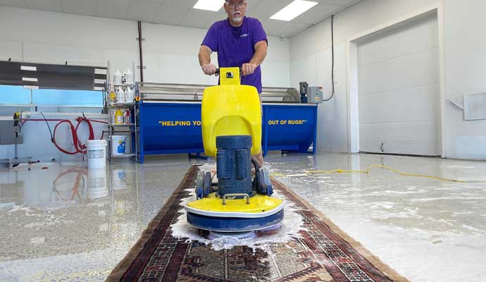 Person cleaning rug with machine